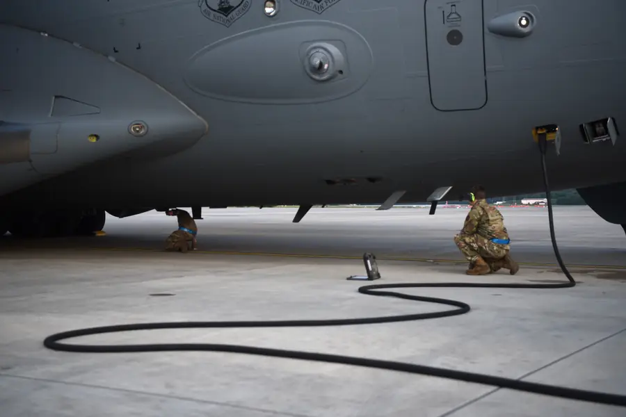 An inspector watching a crew chief inspect a large transport aircraft