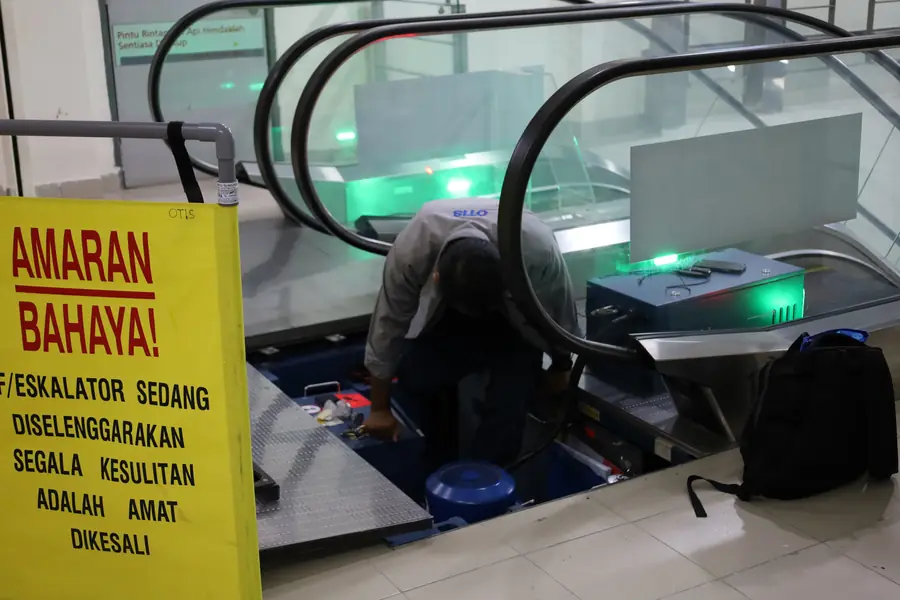 An escalator opened up for maintenance, with a warning sign