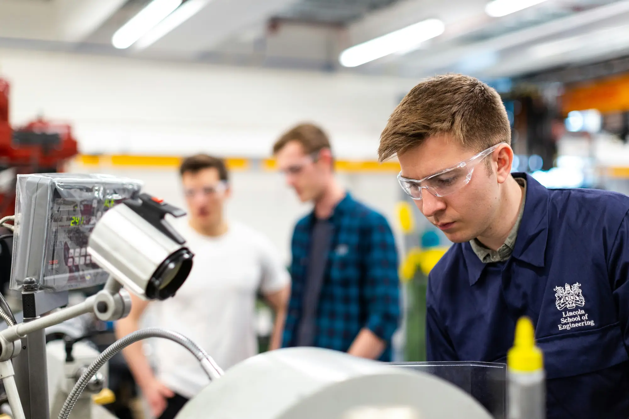 An engineer in safety glasses operating machinery in a workshop