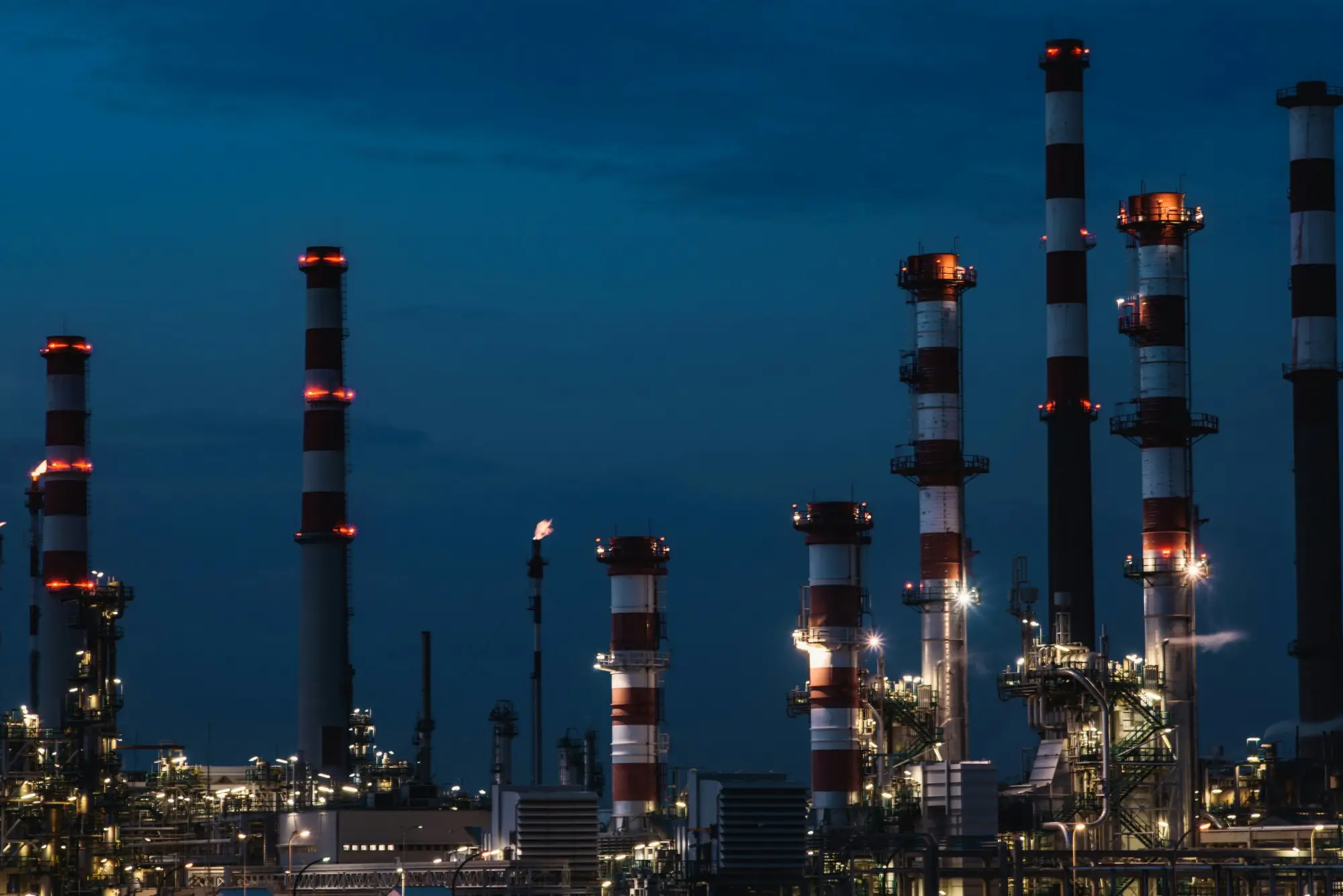 Refinery stacks and process units lit up at dusk