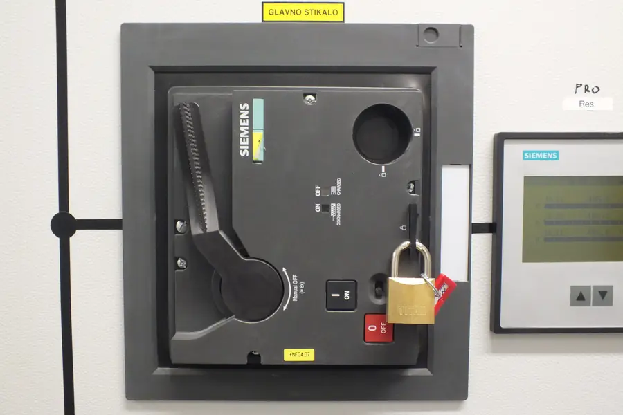 A main electrical switch locked out with a padlock and a warning tag