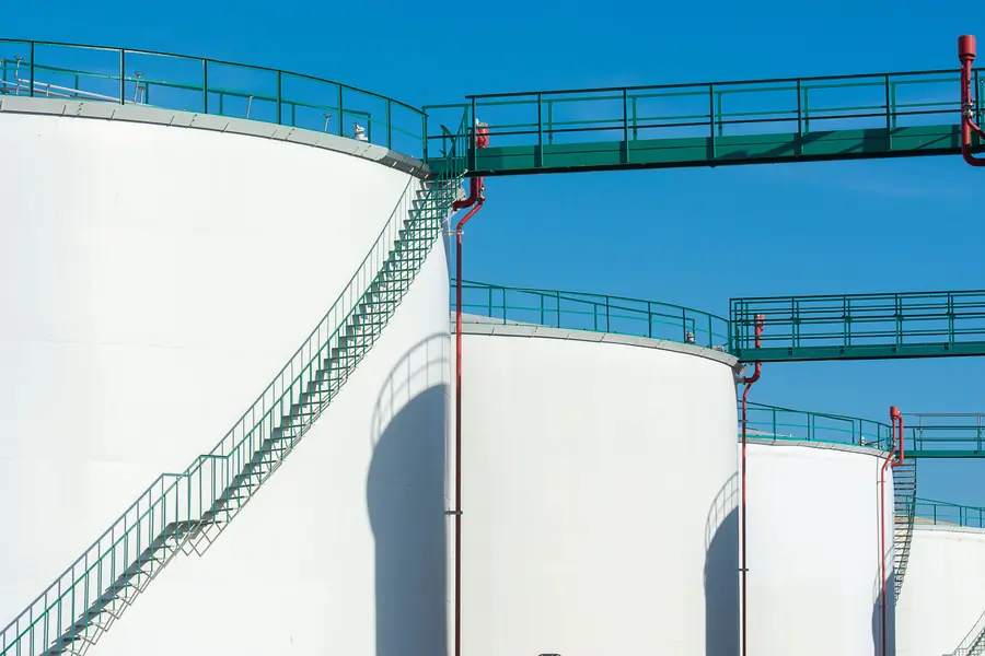 White storage tanks with access stairs against a blue sky