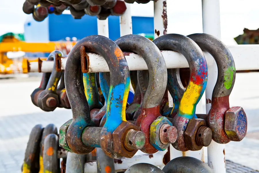Color-coded steel shackles hanging on a rack
