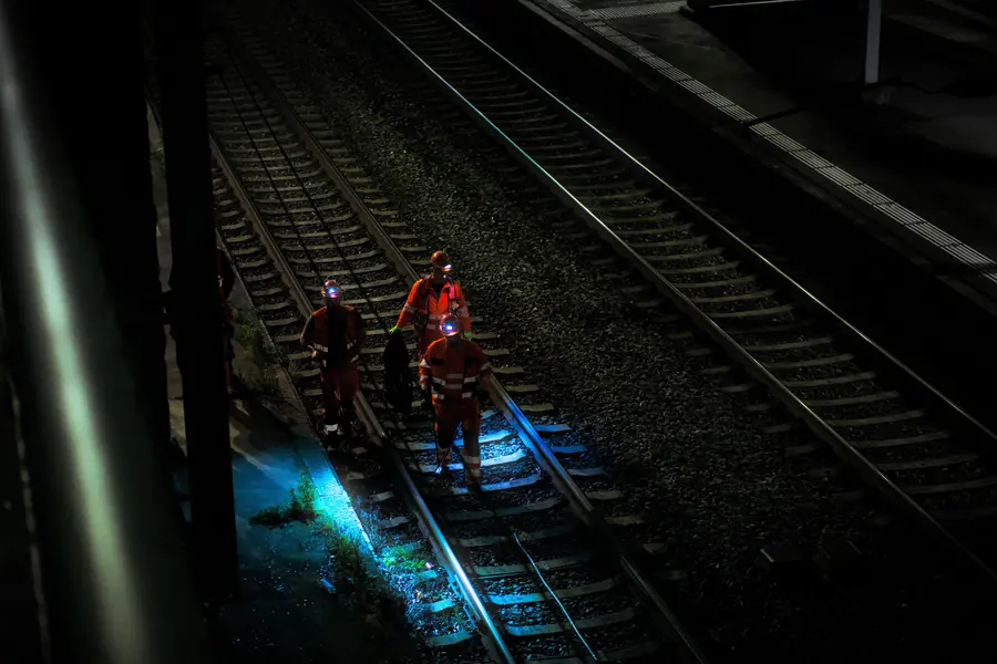 Rail workers on the track at night under work lights