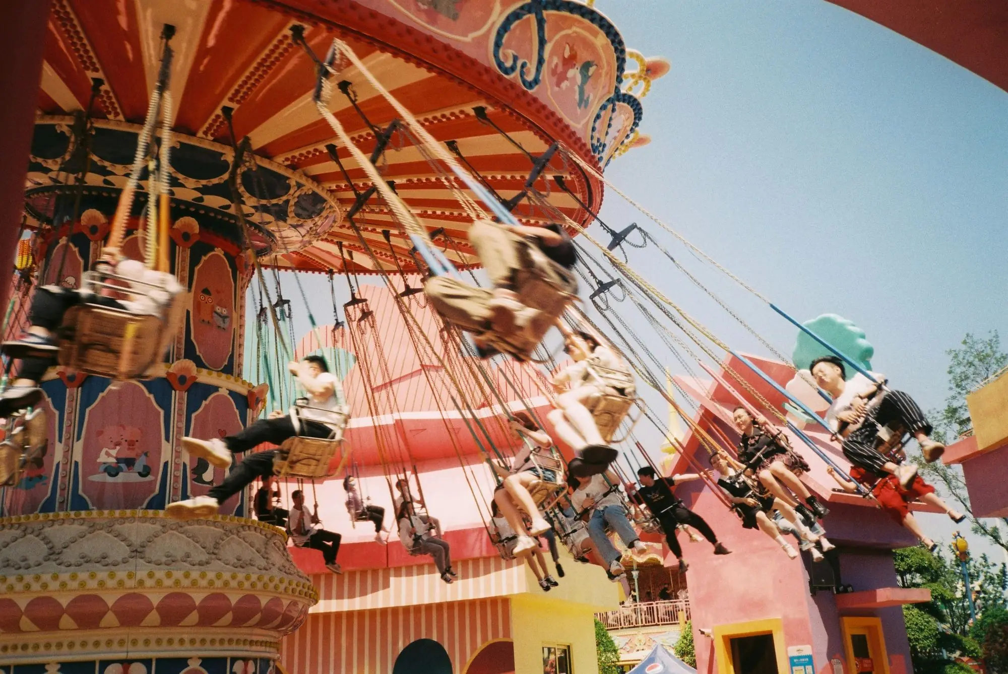 Riders on a swing carousel at an amusement park on a sunny day