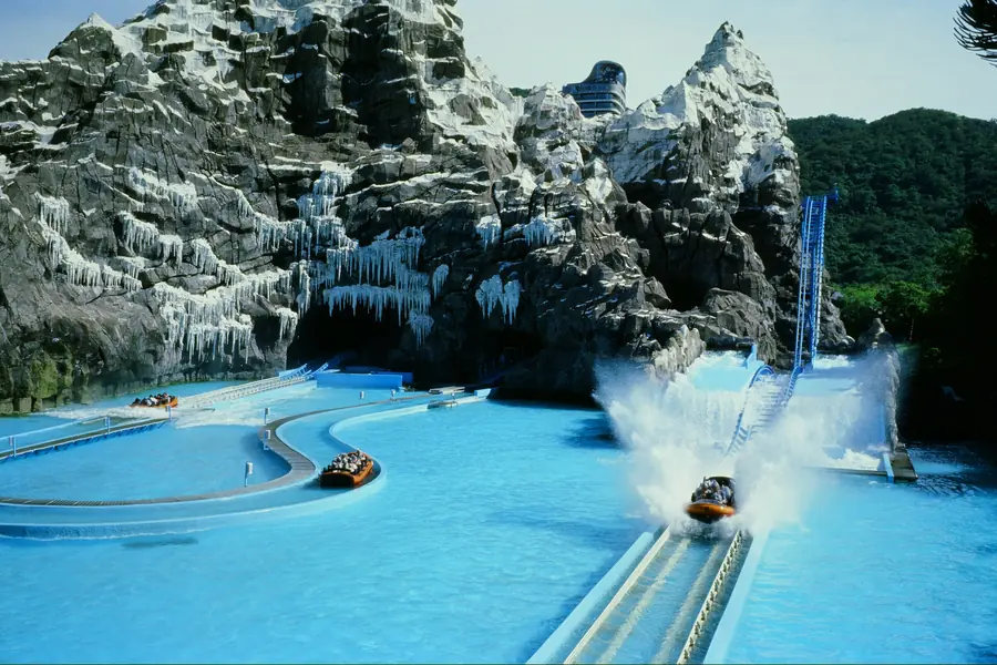 Boats on a water ride splashing down beside an artificial snowy mountain
